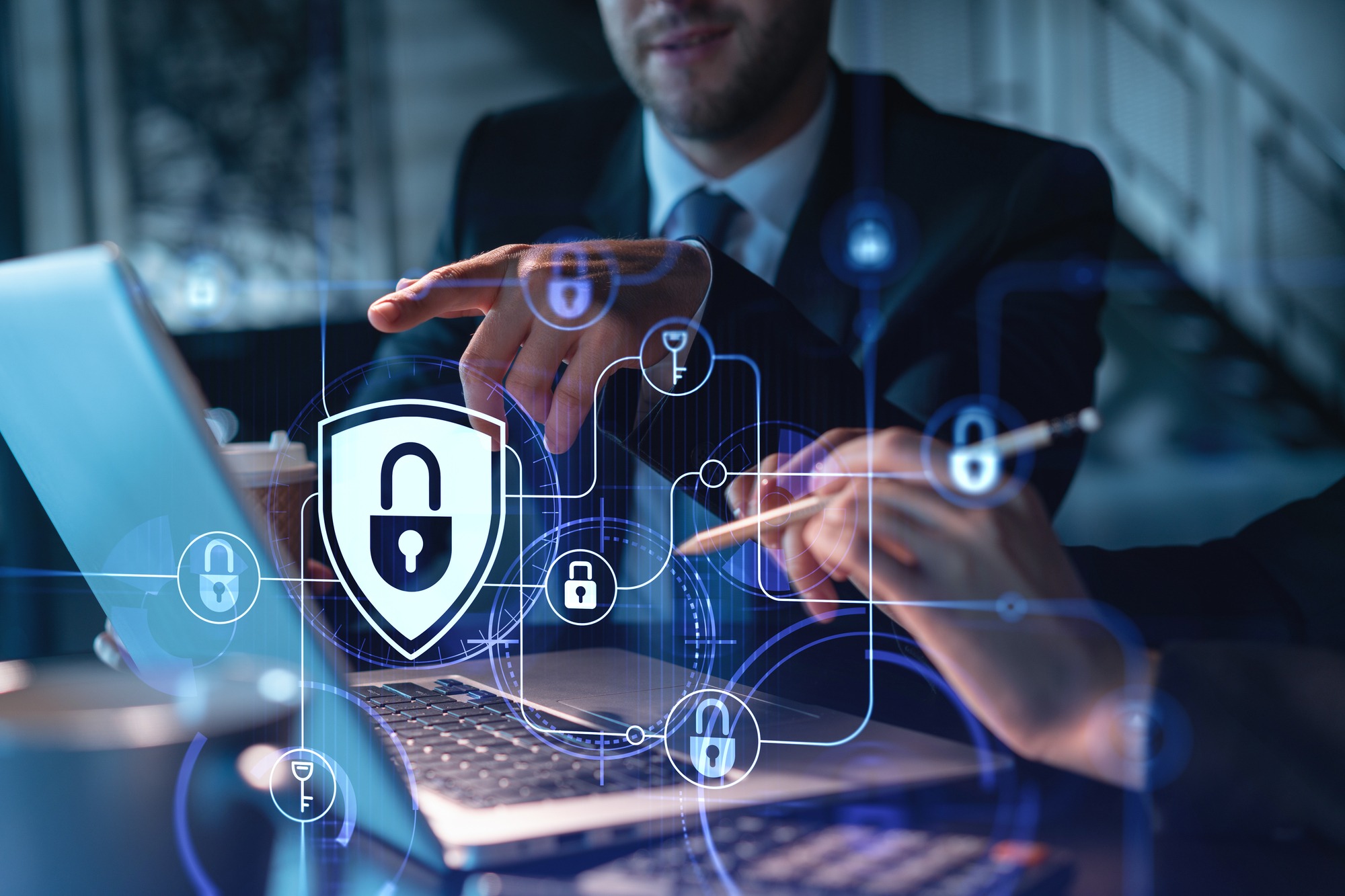 Two Colleagues Working Together to Protect Clients Confidential Information and Cyber Security. It Hologram Padlock Icons Modern Office Background at Night Time.
