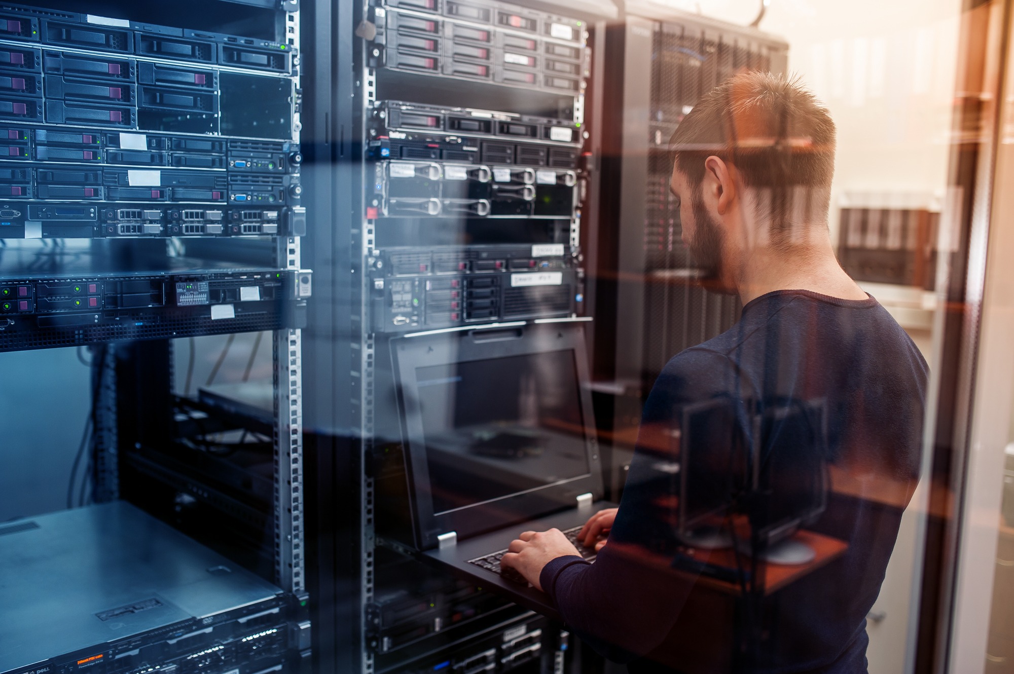 Young It Engeneer Business Man With Thin Modern Aluminium Laptop in Network Server Room.